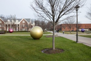 Tan metallic ball behind a tree.