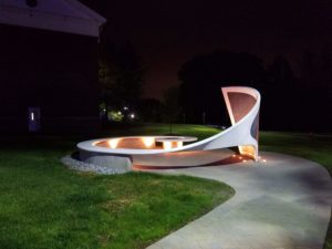 A white circular bench that curves upward into a chalkboard with built in lights.