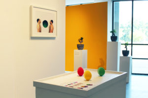 A red, yellow, and green egg-shaped object sitting upon a white table.