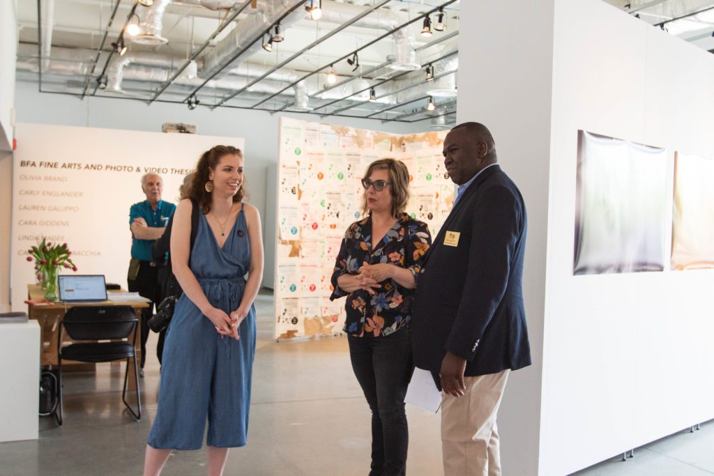 A student and two faculty members looking at the exhibits. 