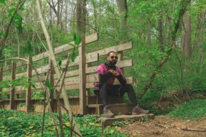 Photo of man sitting on a wooden bridge in the woods