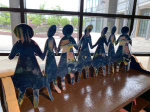 Photograph of an artwork that consists of a chain of paper dolls made from cyanotype images