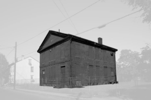 Black and white photo of a segregated school. The brick building is emphasized as a dark grey, while the rest of the landscape is covered with a semi-opaque white sheen.